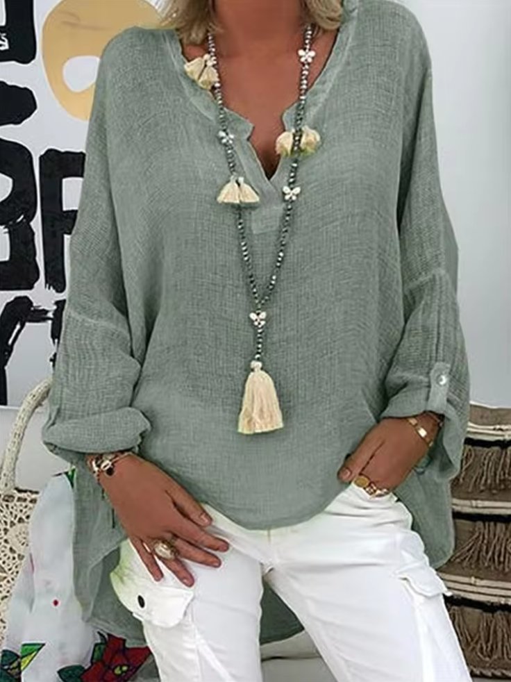 Plus size women’s blouse with V-neckline, roll-tab sleeves, relaxed fit, and curved hem, suitable for work, travel, and everyday wear.