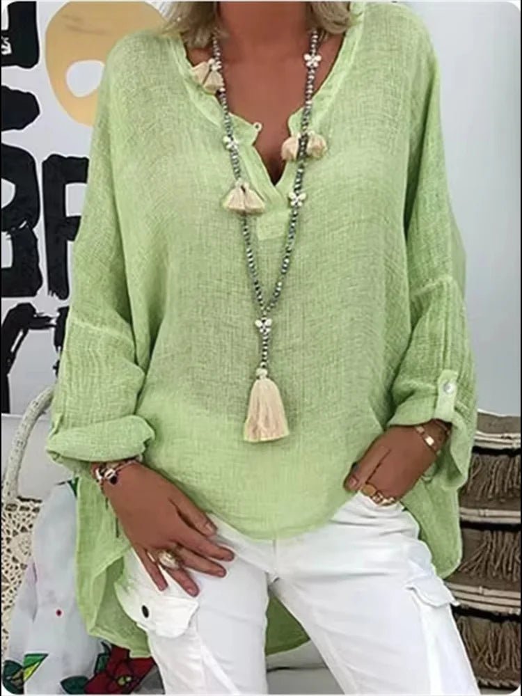 Plus size women’s blouse with V-neckline, roll-tab sleeves, relaxed fit, and curved hem, suitable for work, travel, and everyday wear.