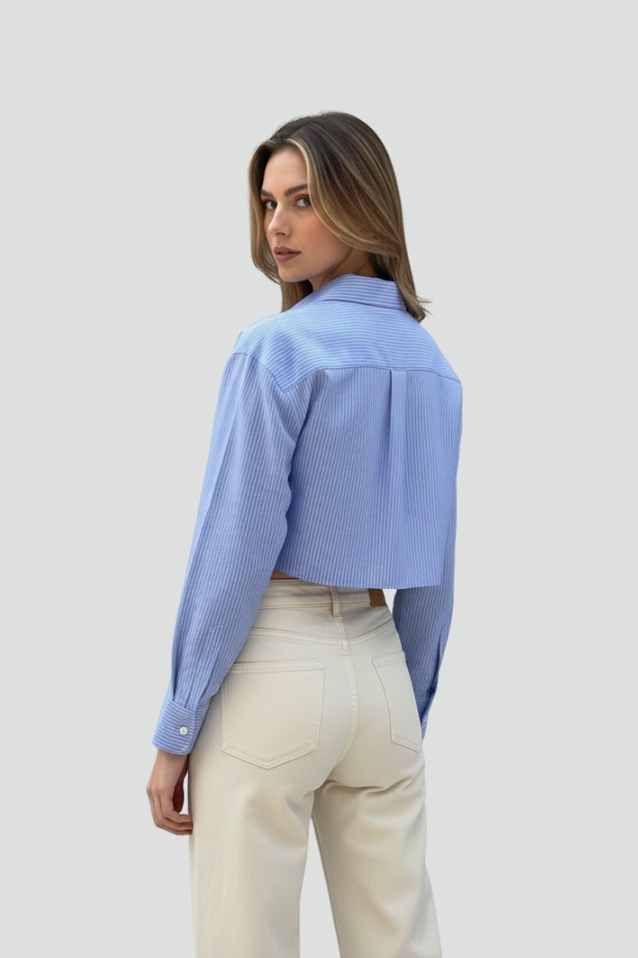 Women’s cropped shirt with pointed collar, button closure, striped pattern, and long sleeves for modern casual styling.