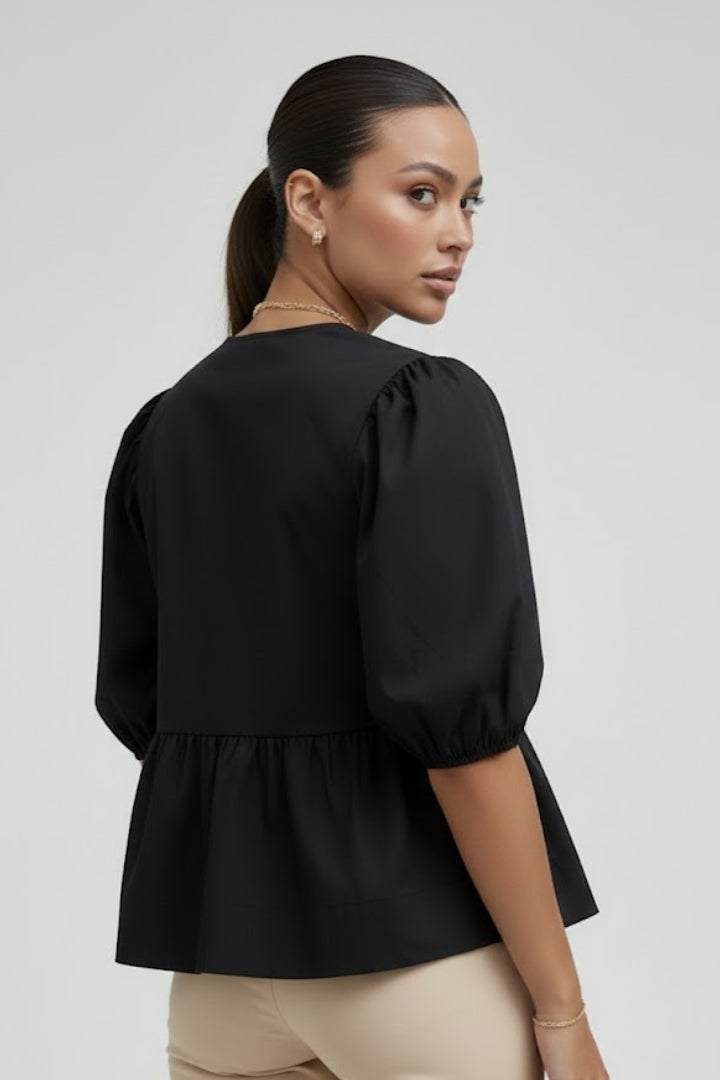 Women’s peplum blouse with bow details, button-down front, puffed sleeves, and flared hem for casual and occasion styling.