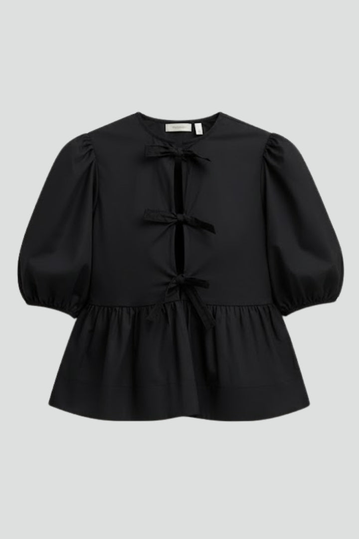 Women’s peplum blouse with bow details, button-down front, puffed sleeves, and flared hem for casual and occasion styling.
